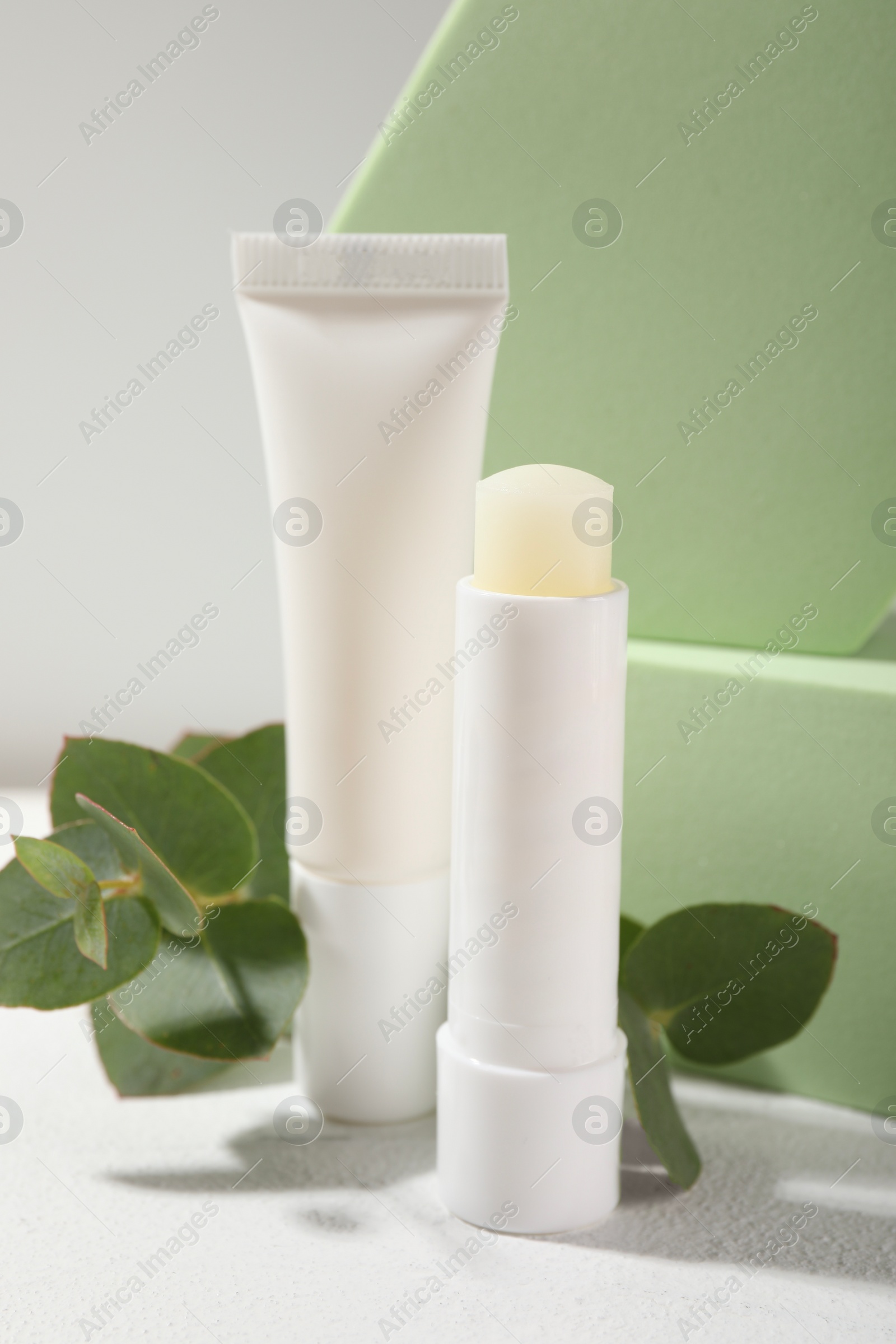 Photo of Stylish presentationdifferent lip balms on white table, closeup