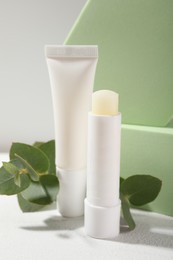 Photo of Stylish presentation of different lip balms on white table, closeup