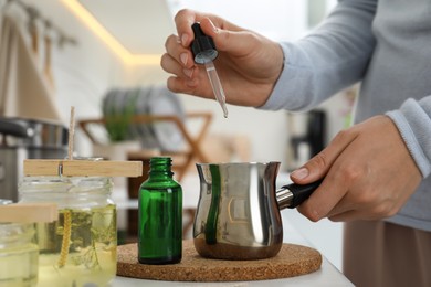 Photo of Woman making aromatic candles at white table indoors, closeup