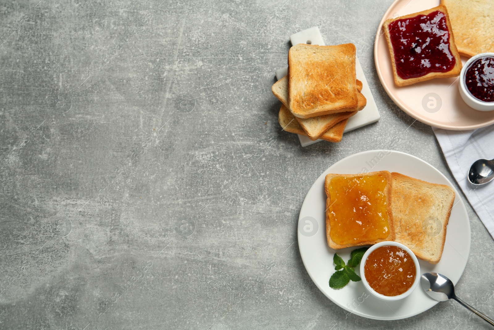 Photo of Delicious toasts with jams served on light grey table, flat lay. Space for text