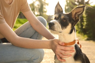 Photo of Teenage girl with her cute dog in park, closeup