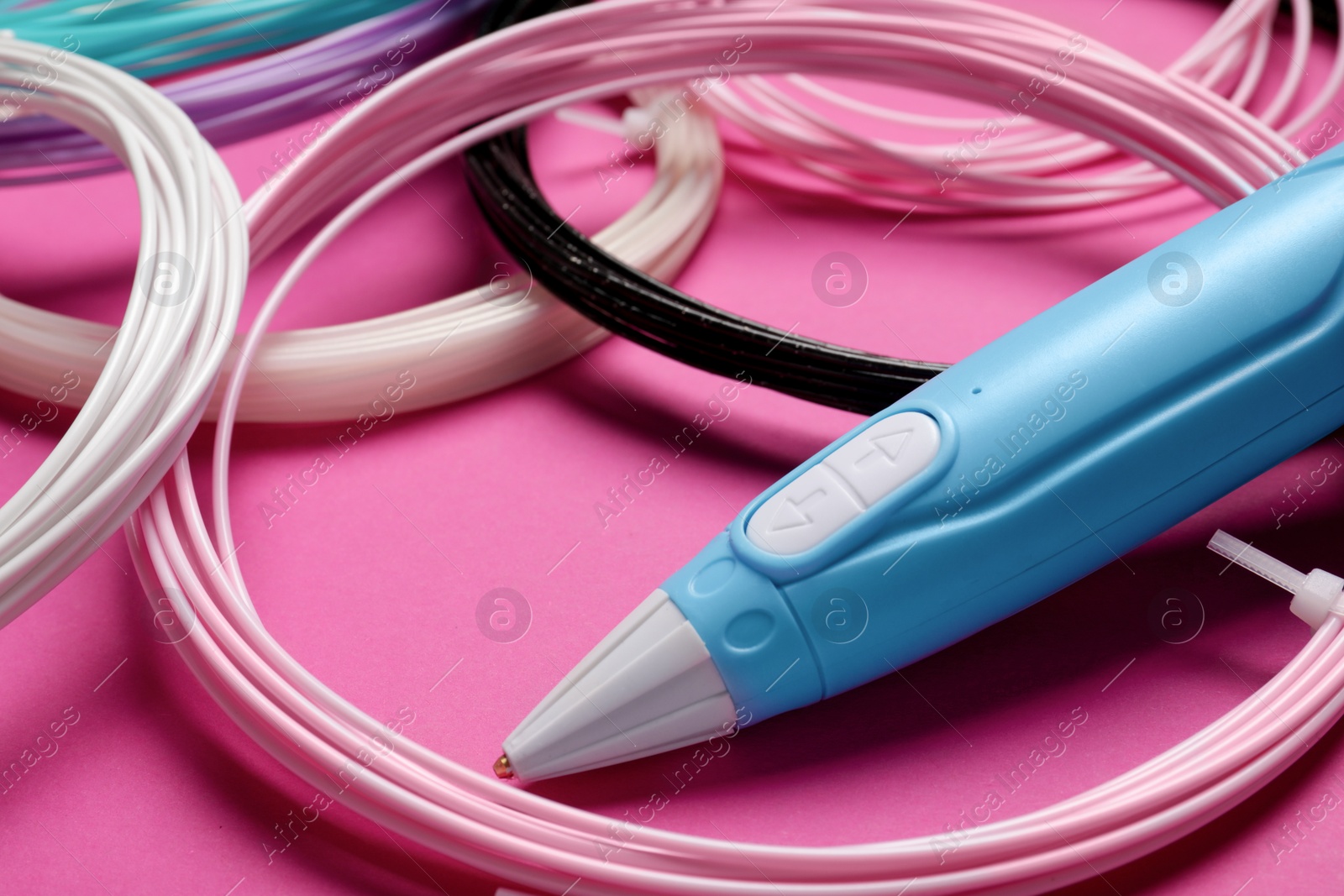 Photo of Stylish 3D pen and colorful plastic filaments on pink background, closeup