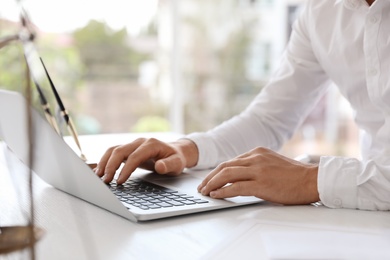 Male notary working with laptop at table in office, closeup