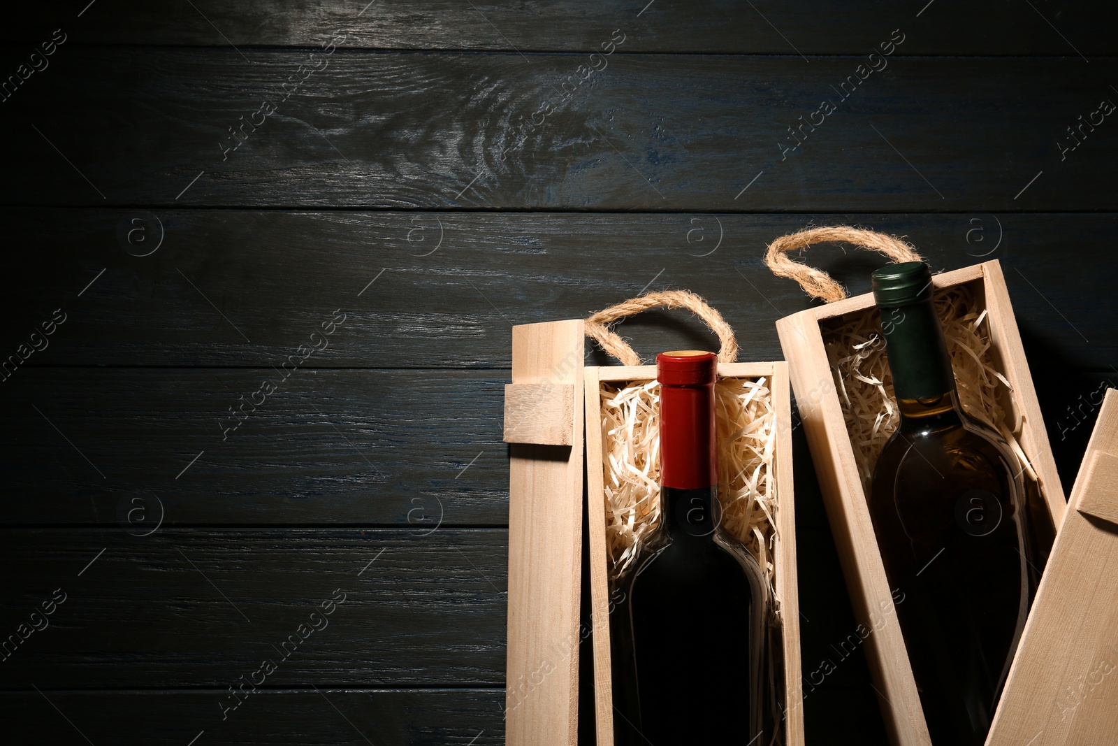 Photo of Crates with bottles of wine on wooden table, flat lay. Space for text