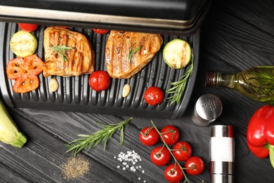 Photo of Flat lay composition with electric grill and different products on black wooden table