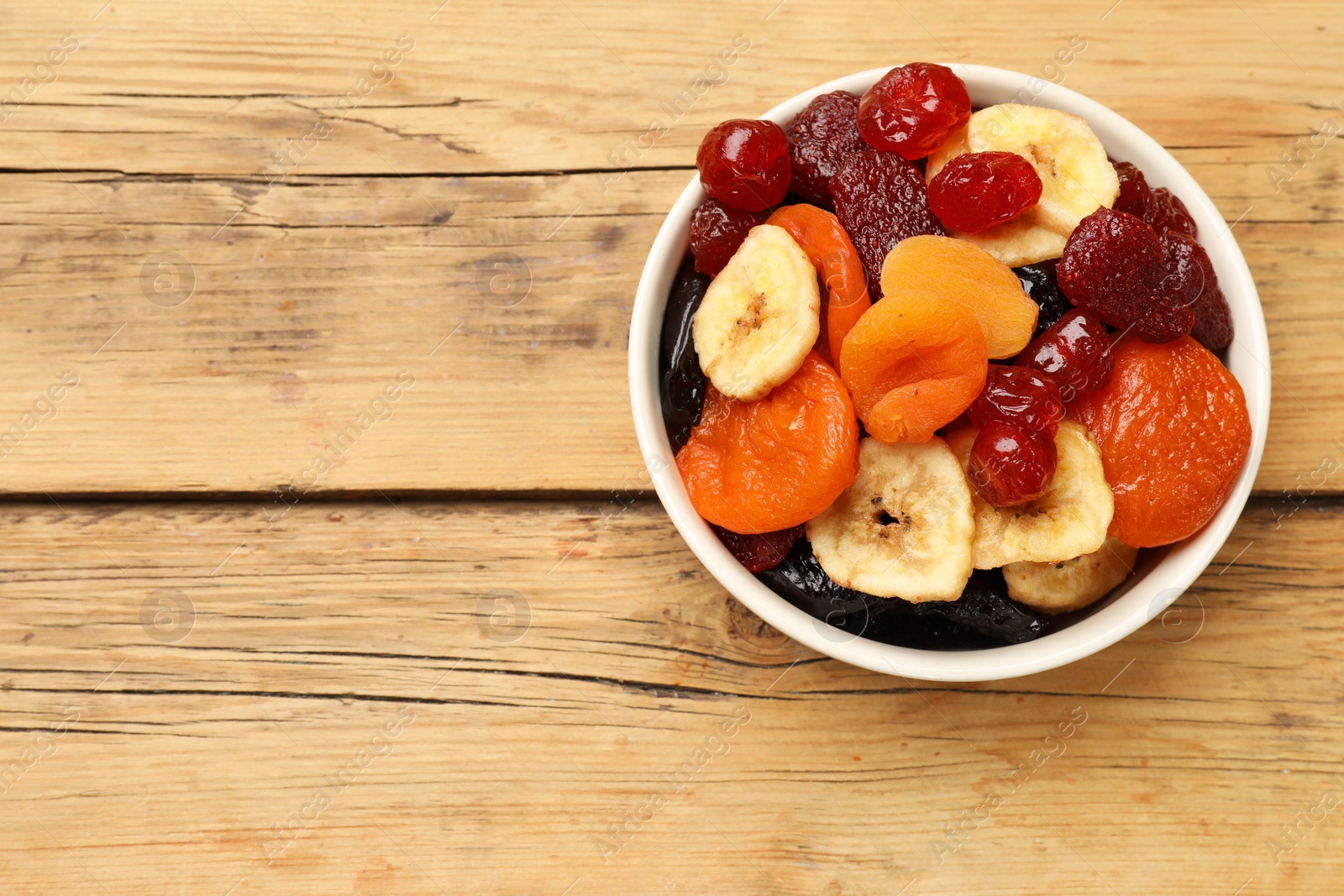 Photo of Mix of delicious dried fruits on wooden table, top view. Space for text