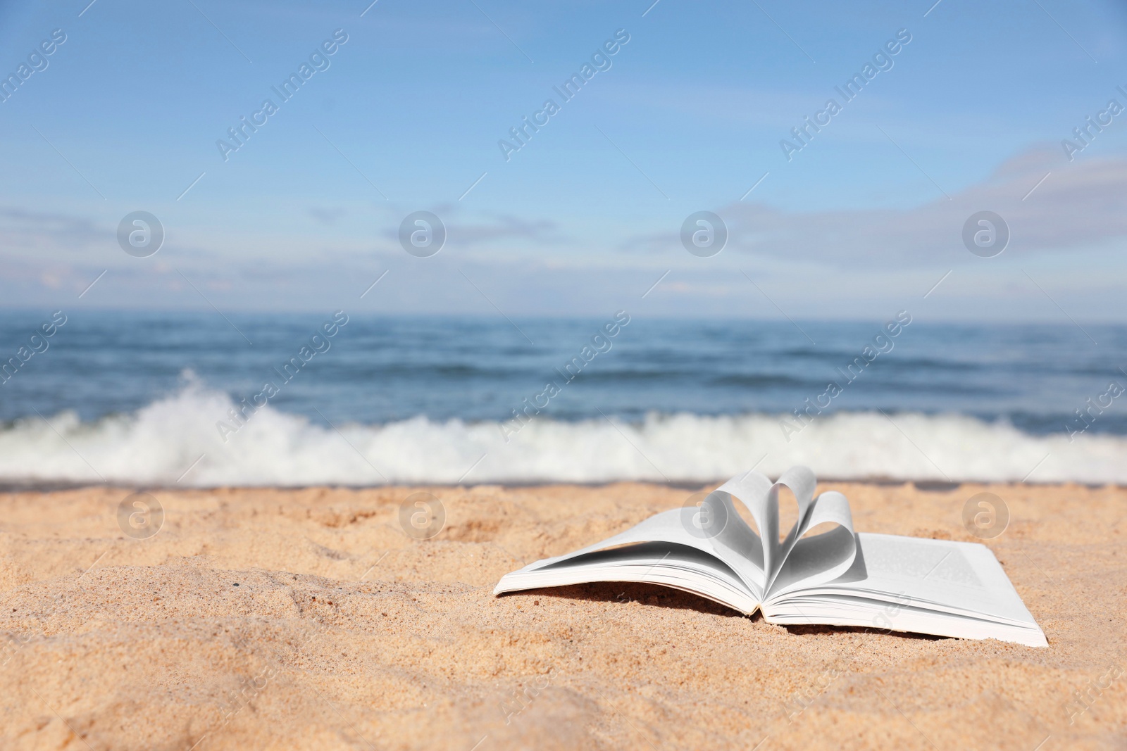 Photo of Open book on sandy beach near sea. Space for text