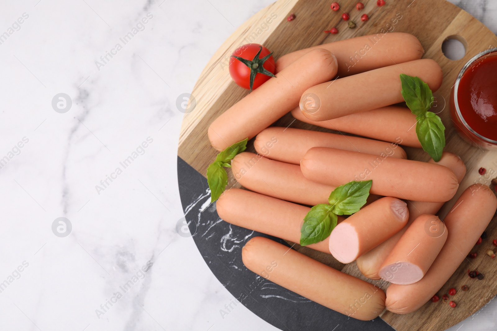 Photo of Delicious boiled sausages with spices, sauce and tomato on white marble table, top view. Space for text