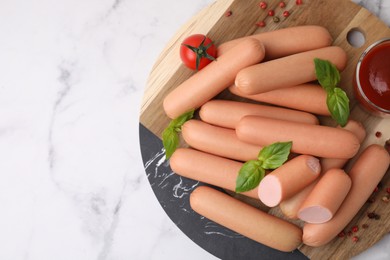 Photo of Delicious boiled sausages with spices, sauce and tomato on white marble table, top view. Space for text