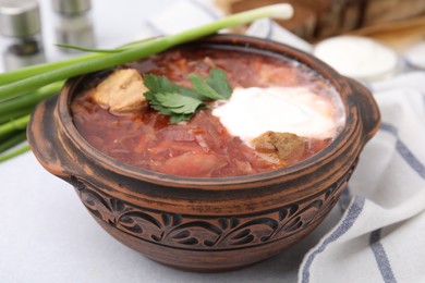 Tasty borscht with sour cream in bowl on light grey table, closeup