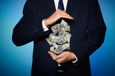 Image of Businessman with money on blue background, closeup. Currency exchange