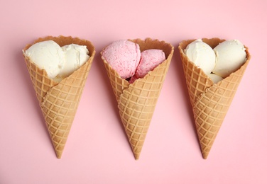 Photo of Delicious ice creams in wafer cones on pink background, flat lay