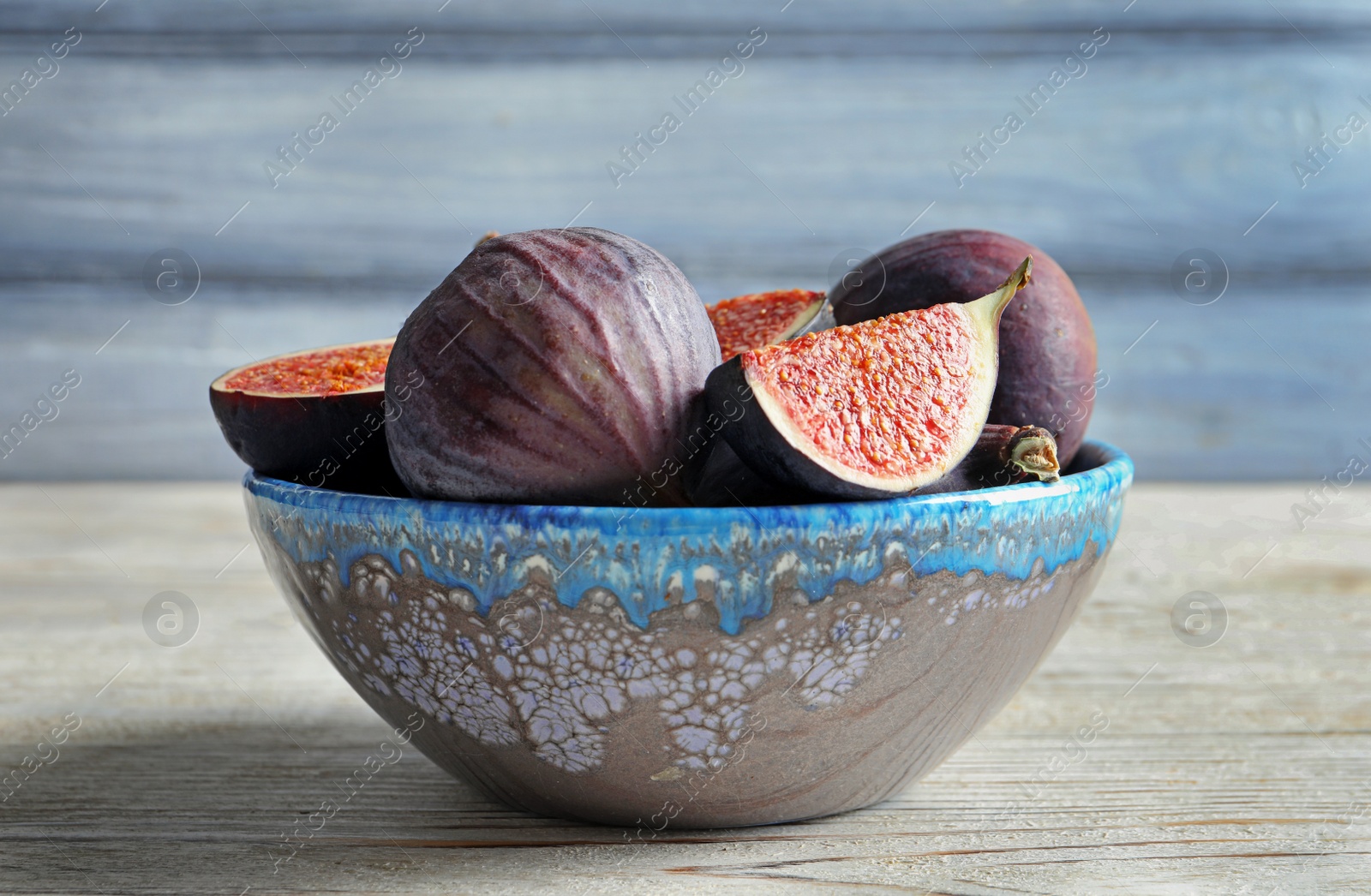 Photo of Bowl with fresh ripe figs on wooden background. Tropical fruit