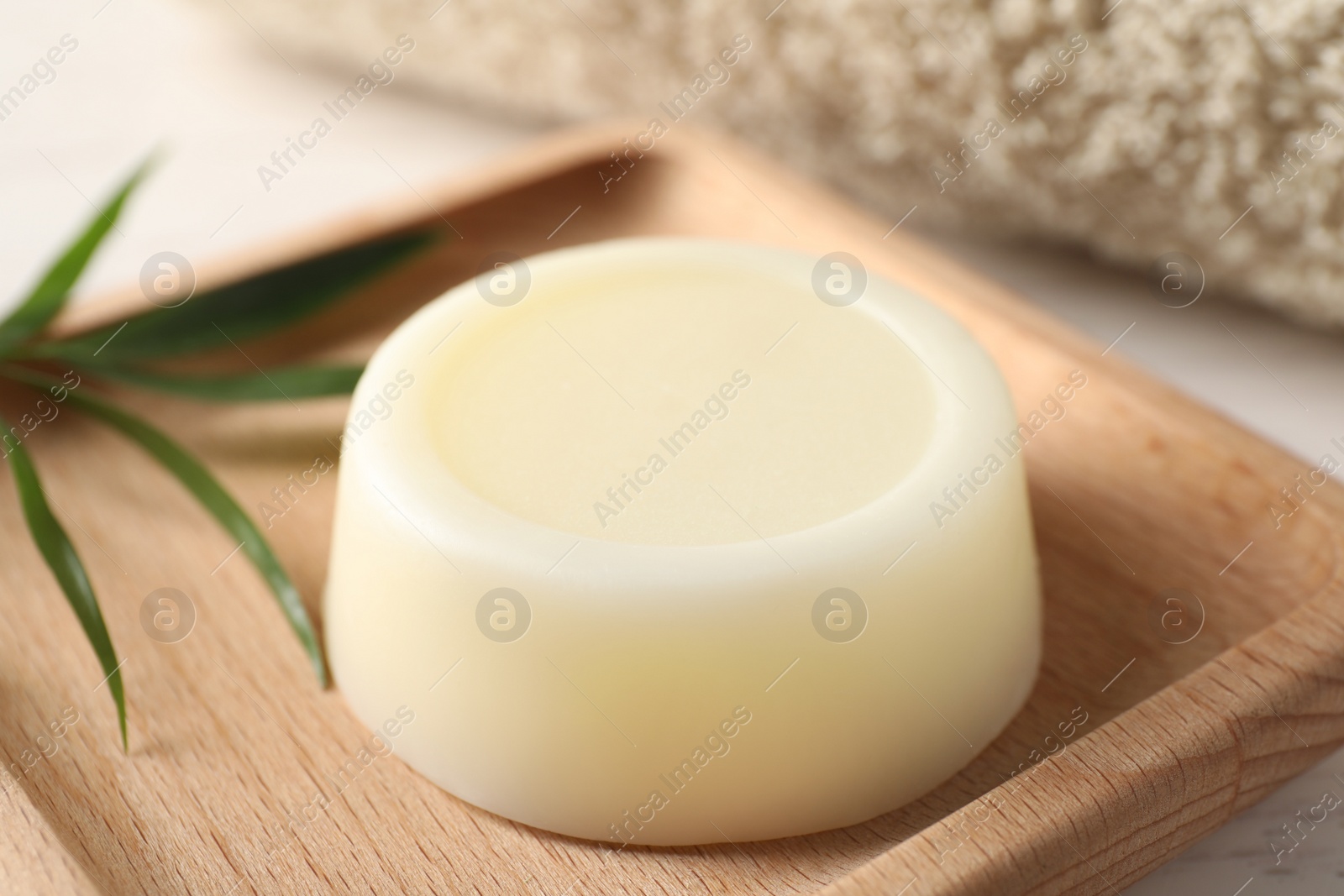 Photo of Dish with solid shampoo bar on white table, closeup