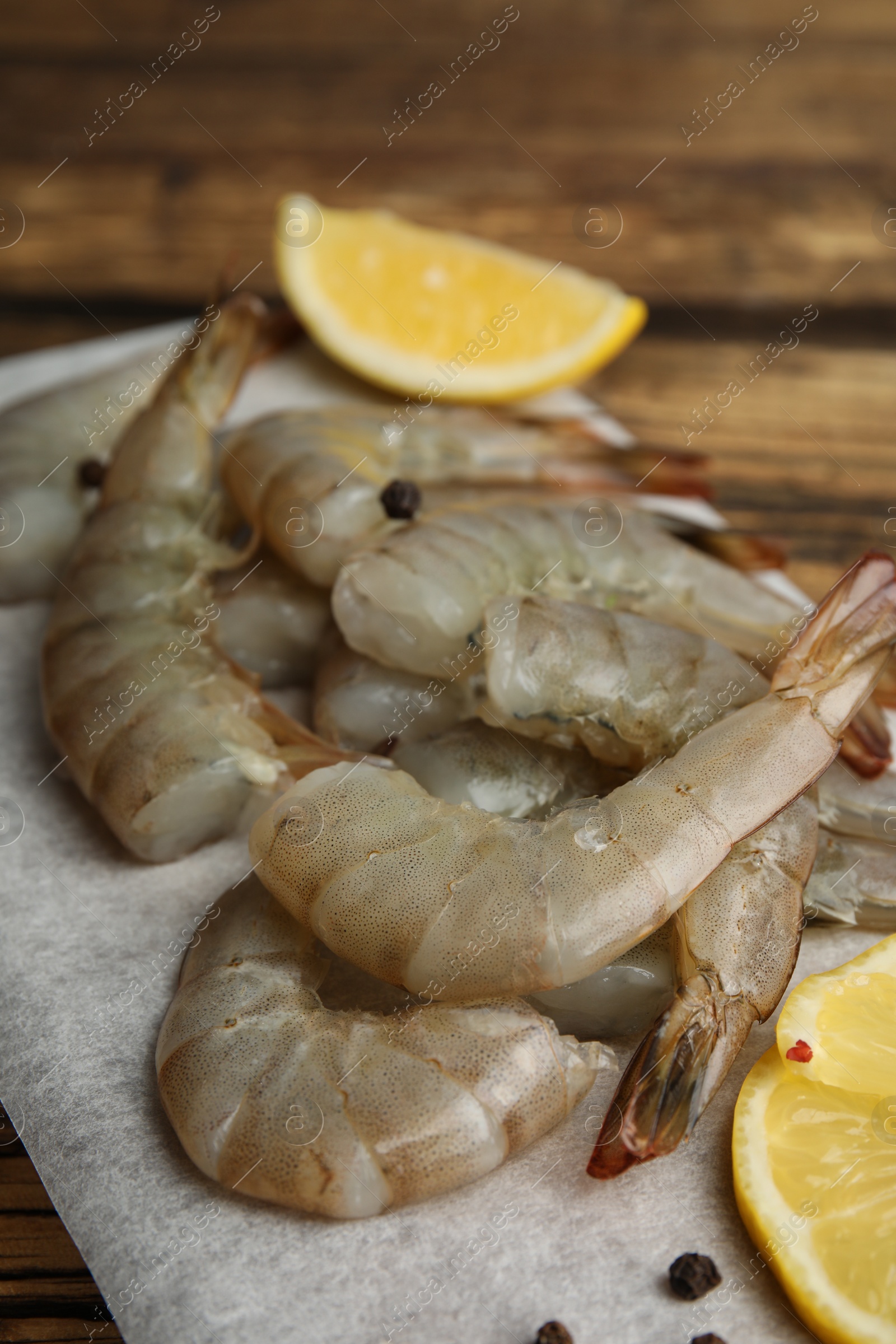 Photo of Fresh raw shrimps with lemon on wooden board, closeup