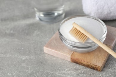 Photo of Bamboo toothbrush and glass bowl of baking soda on light grey table, space for text