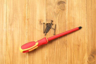 Photo of Screwdriver with red handle and screws on table, flat lay