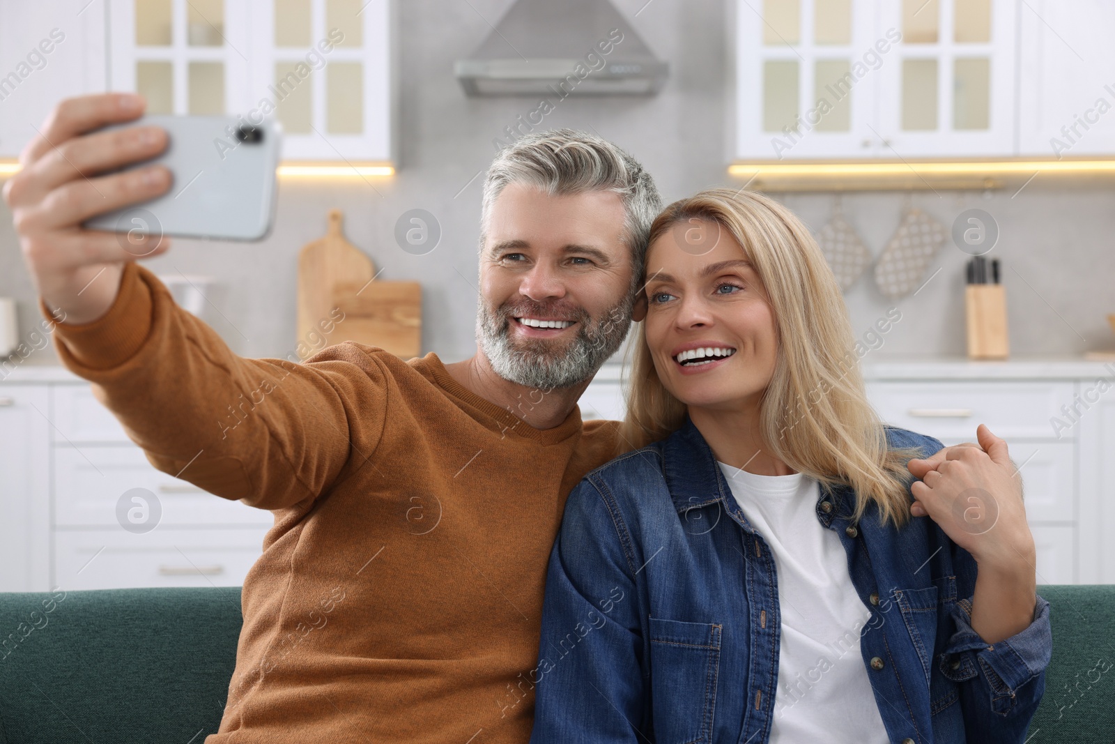 Photo of Happy affectionate couple taking selfie on sofa at home. Romantic date