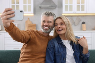 Photo of Happy affectionate couple taking selfie on sofa at home. Romantic date