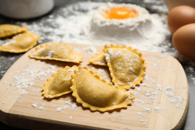 Photo of Raw ravioli on wooden board, closeup view. Italian pasta