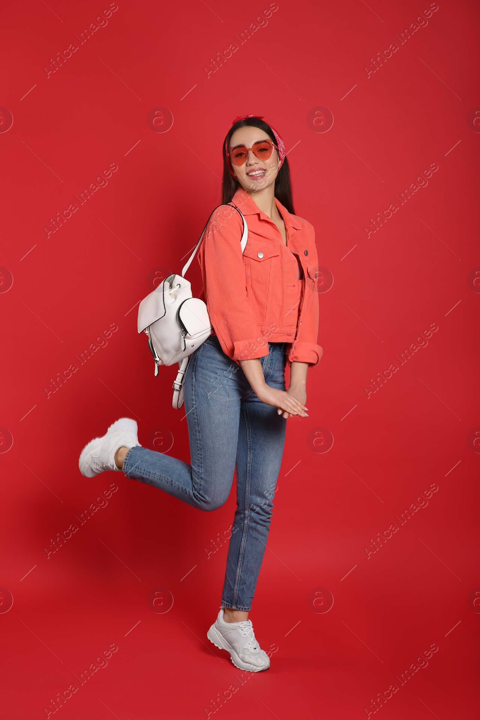 Photo of Beautiful young woman with stylish leather backpack on red background