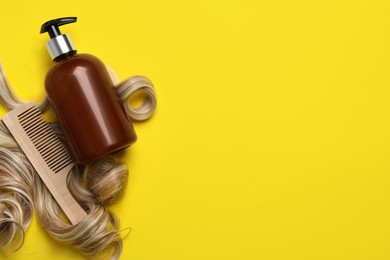 Photo of Lock of healthy blond hair, cosmetic product and comb on yellow background, flat lay. Space for text
