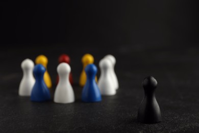 Photo of Black pawn standing out from other ones on dark background, closeup. Racism concept