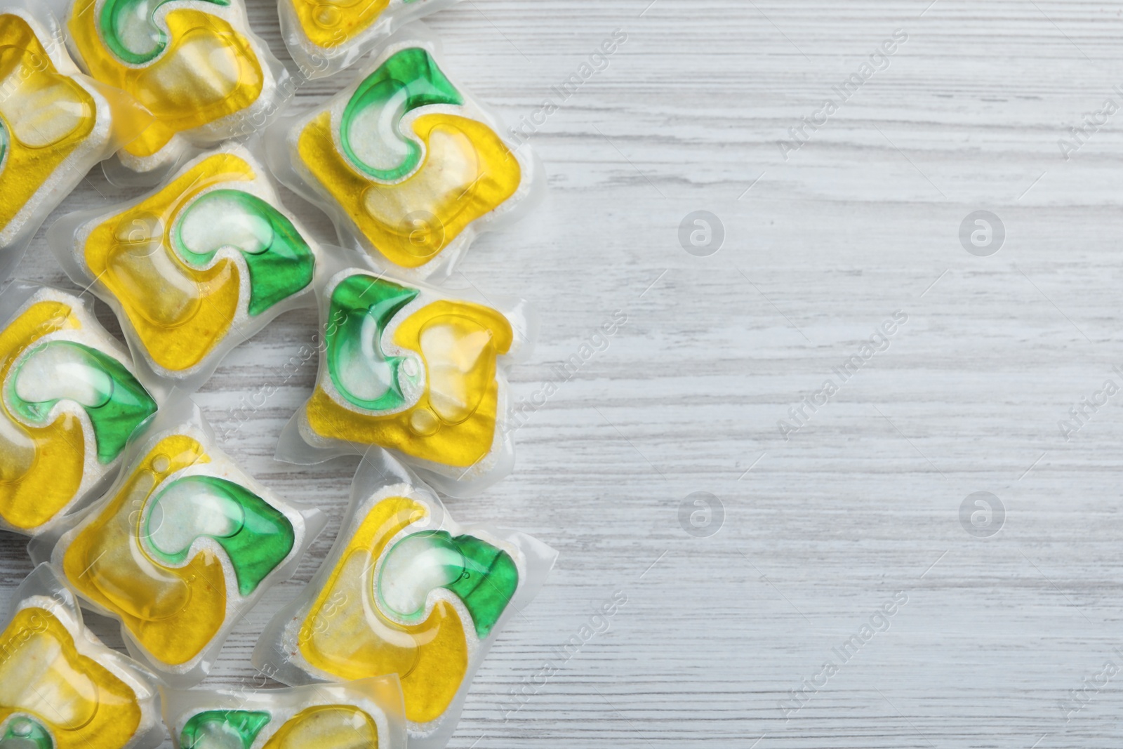 Photo of Many dishwasher detergent pods on white wooden table, flat lay. Space for text