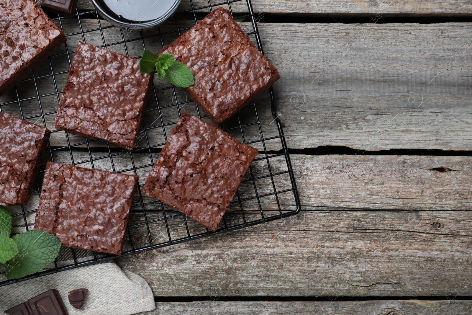 Photo of Cooling rack with delicious chocolate brownies and fresh mint on wooden table, flat lay. Space for text