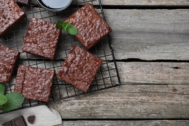 Cooling rack with delicious chocolate brownies and fresh mint on wooden table, flat lay. Space for text