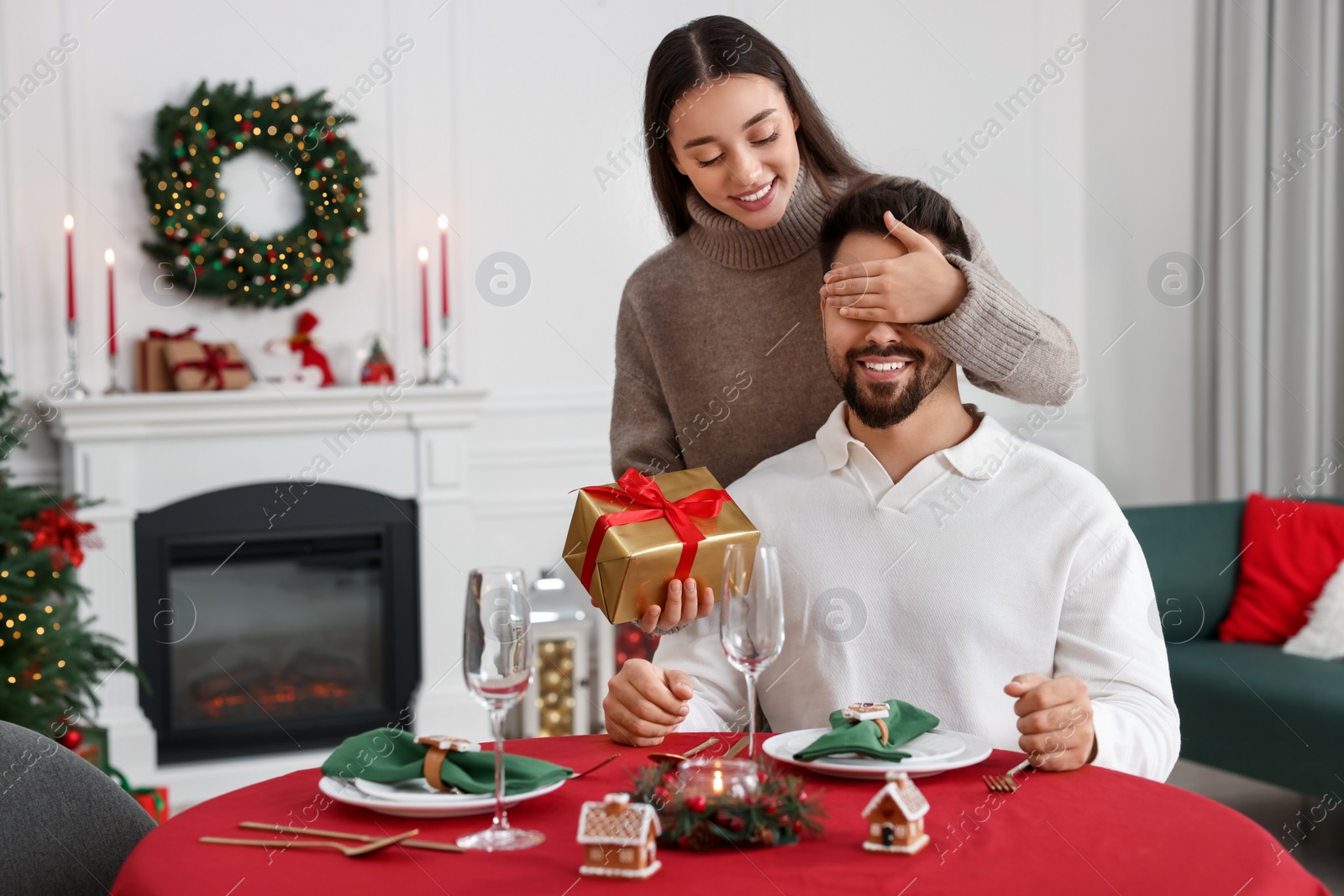 Photo of Happy woman surprising her boyfriend with Christmas gift at home