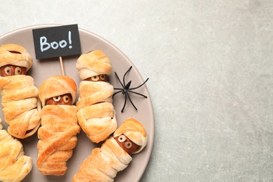 Photo of Spooky sausage mummies for Halloween party served on light grey table, top view. Space for text