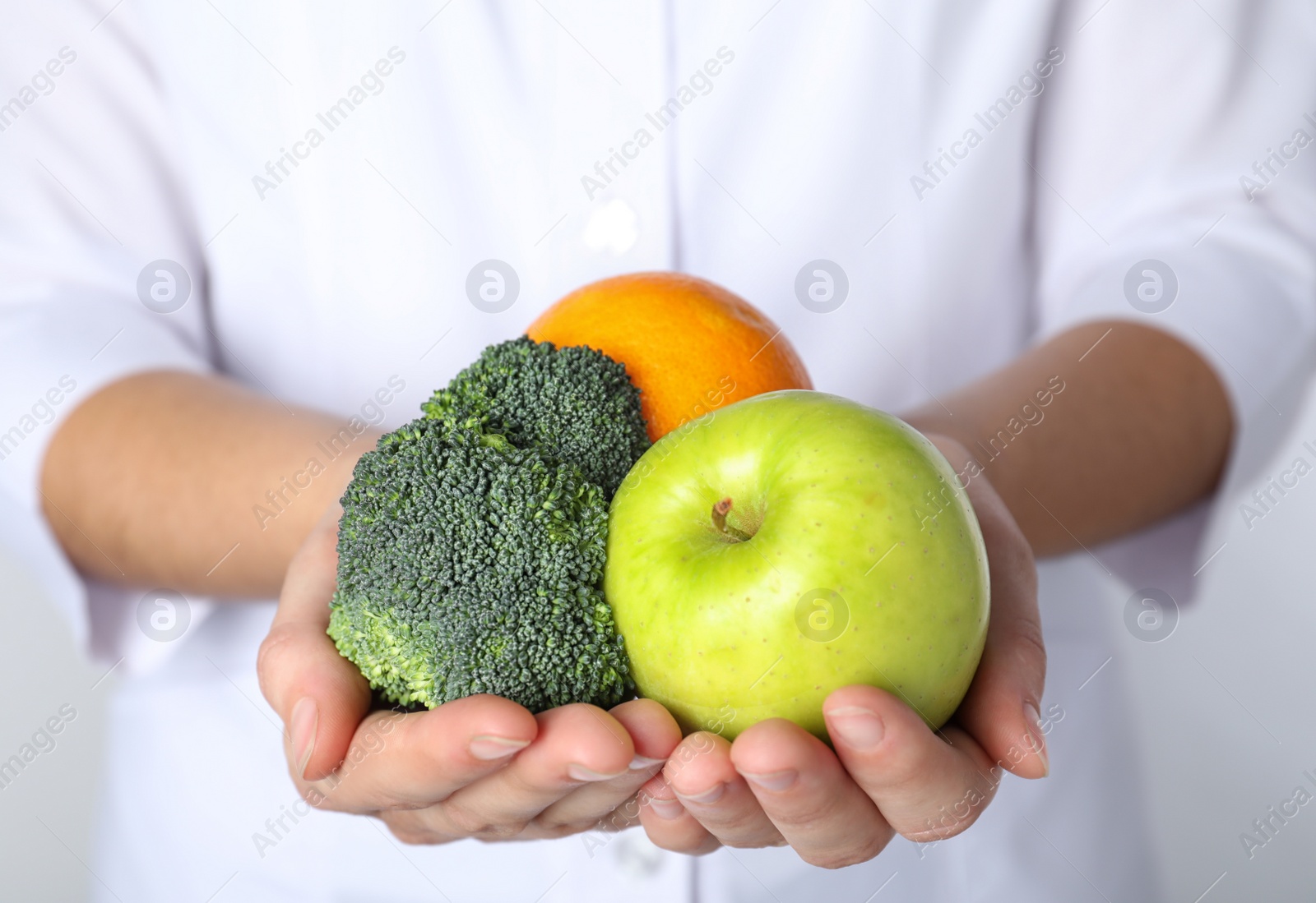 Photo of Female nutritionist with products on light background, closeup