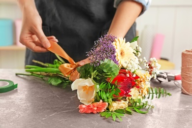 Photo of Female florist making beautiful bouquet at table