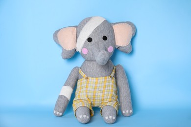 Toy elephant with bandages on light blue background