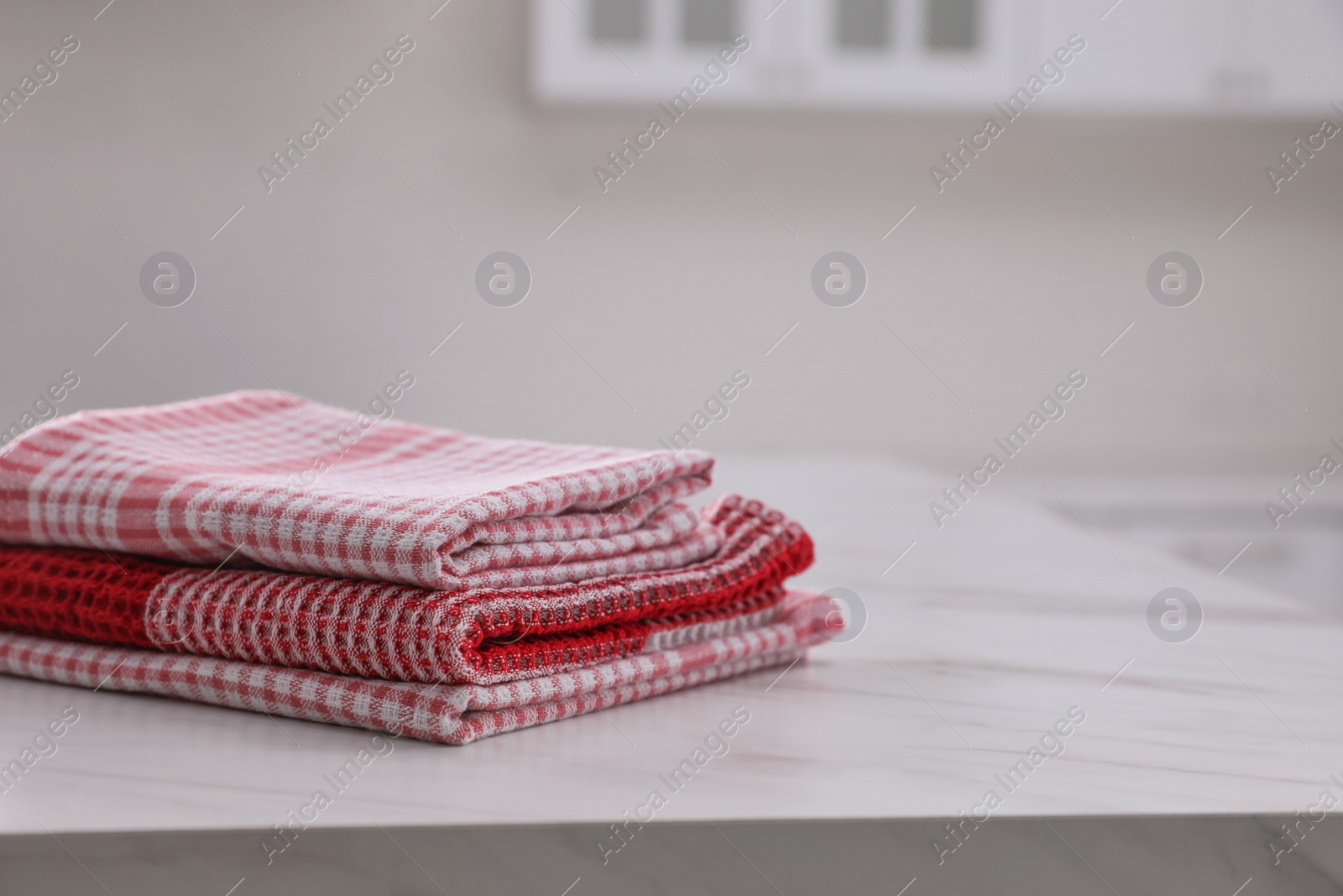 Photo of Stack of kitchen towels on white marble table. Space for text