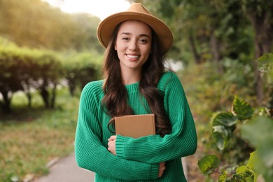 Photo of Beautiful young woman in stylish warm sweater with book outdoors