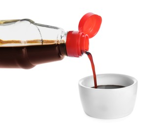 Photo of Pouring soy sauce into bowl against white background