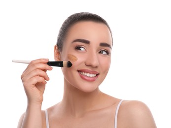 Woman applying foundation on face with brush against white background