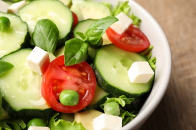 Photo of Tasty fresh salad with cucumber in bowl on table, closeup