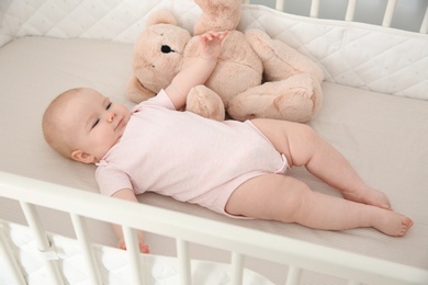 Cute baby girl with toy in crib. Bedtime schedule
