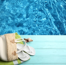 Beach accessories on turquoise wooden deck near swimming pool, flat lay. Space for text 