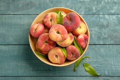 Fresh ripe donut peaches on light blue wooden table, top view