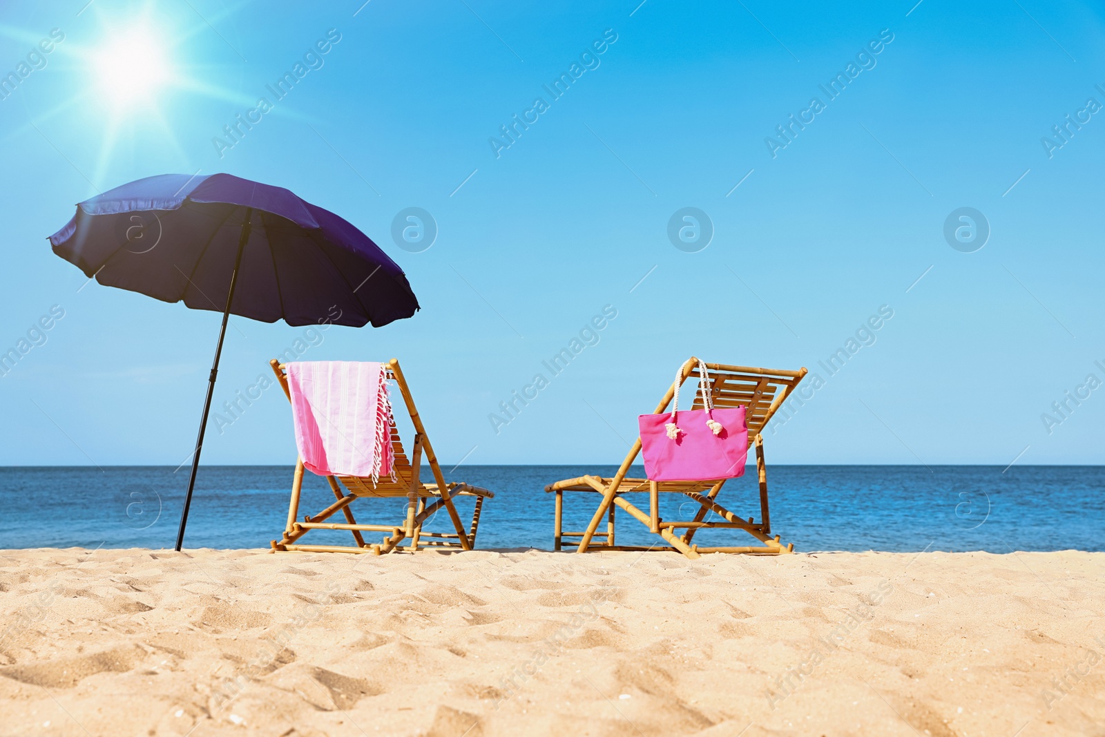 Photo of Empty wooden sunbeds and beach accessories on sandy shore