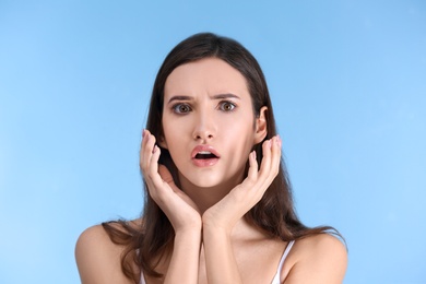 Teenage girl with acne problem against color background