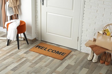 Doormat with word Welcome on wooden floor in hall