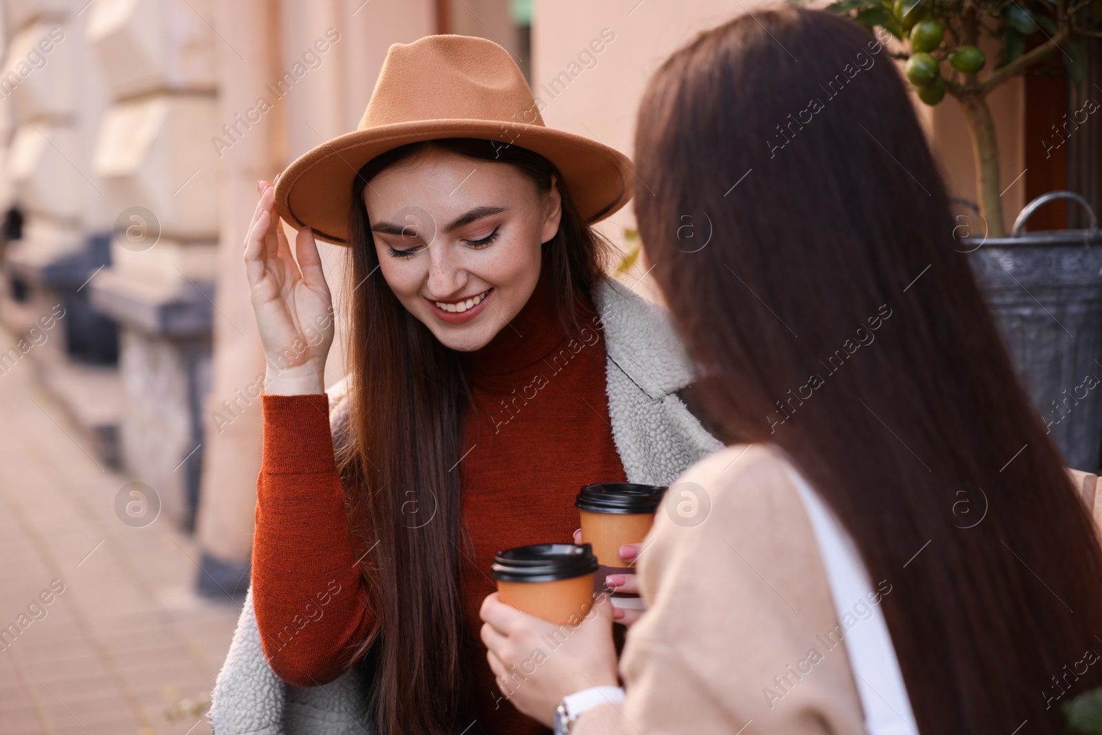 Photo of Happy friends with paper cups of coffee outdoors