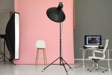 Photo of Pink photo background, workplace and professional lighting equipment in modern studio