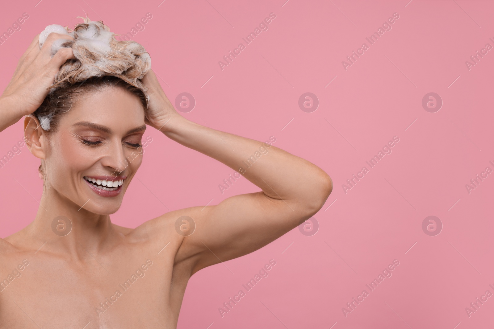 Photo of Beautiful happy woman washing hair on pink background. Space for text