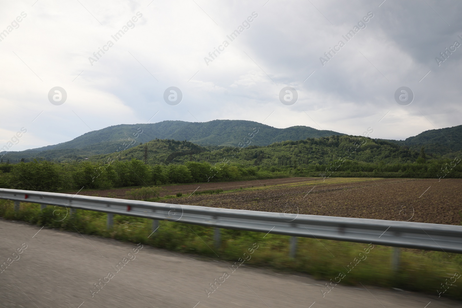 Photo of Picturesque view of asphalt road near mountains on cloudy day